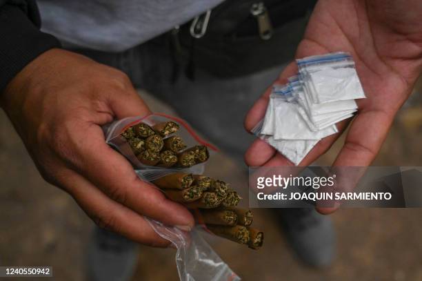 Drug dealer shows cocaine and marijuana packages at a park in downtown Medellin, Colombia, on March 23, 2022. - Three decades after Pablo Escobar's...