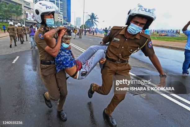 Policemen carry an injured man during a clash between government supporters and demonstrators outside the President's office in Colombo on May 9,...
