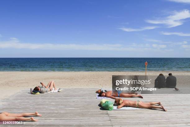 People sunbathing at Dolphin Beach near a 'careful mines' sign. The beaches are mined due to the possible landing of military troops by the Russian...