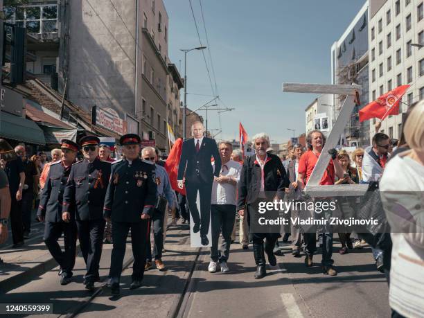 Man holds a cutout of Russian President Vladimir Putin during the "Immortal Regiment" march on May 9, 2022 in Belgrade, Serbia. About 200 people took...