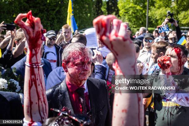 Russian Ambassador to Poland, Ambassador Sergey Andreev reacts after being covered with red paint during a protest prior a ceremony at the Soviet...