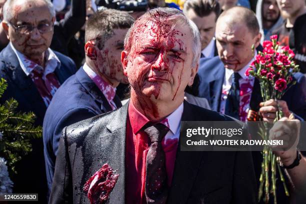 Russian Ambassador to Poland, Ambassador Sergey Andreev reacts after being covered with red paint during a protest prior a ceremony at the Soviet...