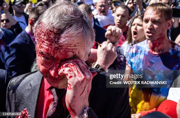 Russian Ambassador to Poland Sergey Andreev wipes his eye after being splattered with a red substance by pro-Ukraine activists in Warsaw on May 9,...