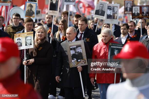 Russian President Vladimir Putin holds a portrait of his father during the Immortal Regiment, a rally where people carrying portraits of their...