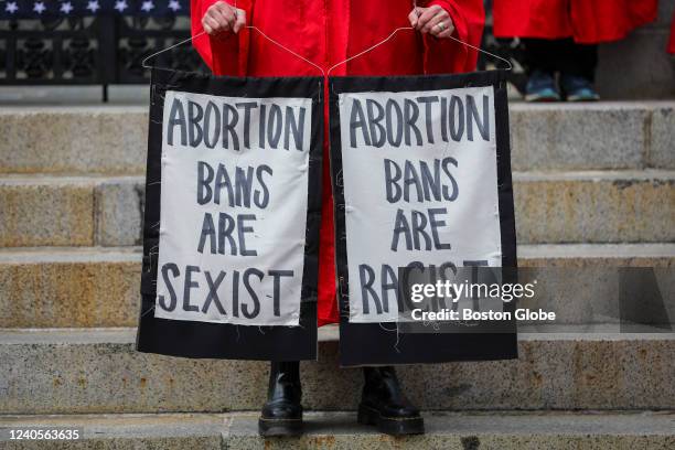 Members of The Boston Red Cloaks carried signs hung from clothing hangers reading abortion bans are sexist and racist in Boston on May 7, 2022....