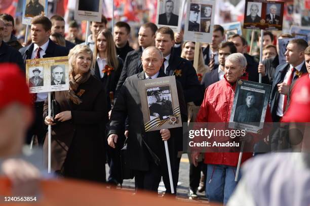 Russian President Vladimir Putin holds a portrait of his father during the Immortal Regiment, a rally where people carrying portraits of their...