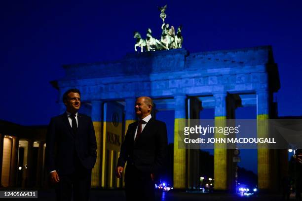 German Chancellor Olaf Scholz and French President Emmanuel Macron visit the landmark Brandenburg Gate illuminated in the colors of the Ukrainian...