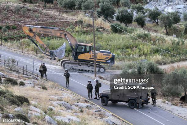 Israeli soldiers protect a bulldozer that demolished a Palestinian house. Clashes erupted between the Palestinians and the Israeli soldiers after...