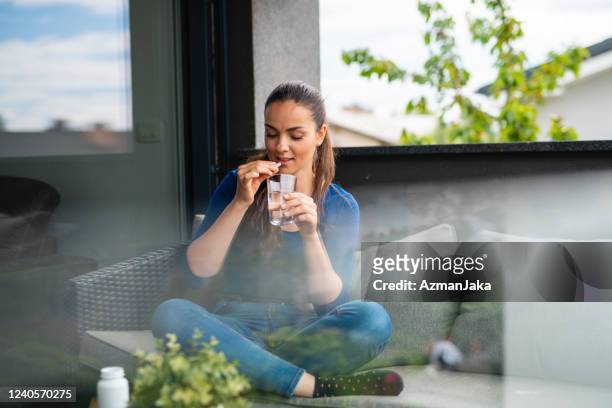 girl sitting on the balcony and eating nutritional supplement pills - moving activity stock pictures, royalty-free photos & images