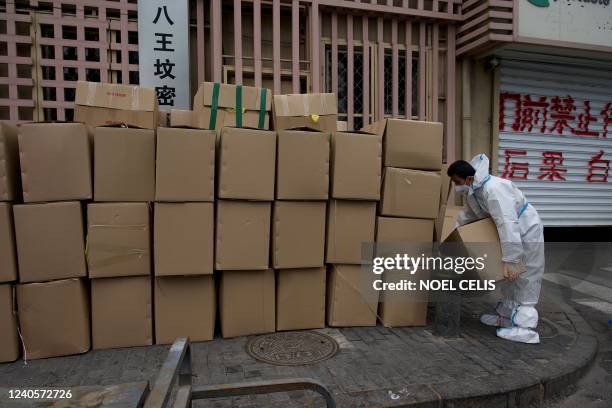 Worker wearing personal protective equipment arranges boxes near the entrance to a residential area on lockdown due to the recent Covid-19...