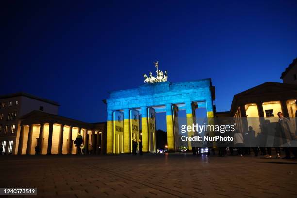 French President Emmanuel Macron and German Chancellor Olaf Scholz visit the Brandenburg Gate enlightened with the colours of the Ukrainian flag in...