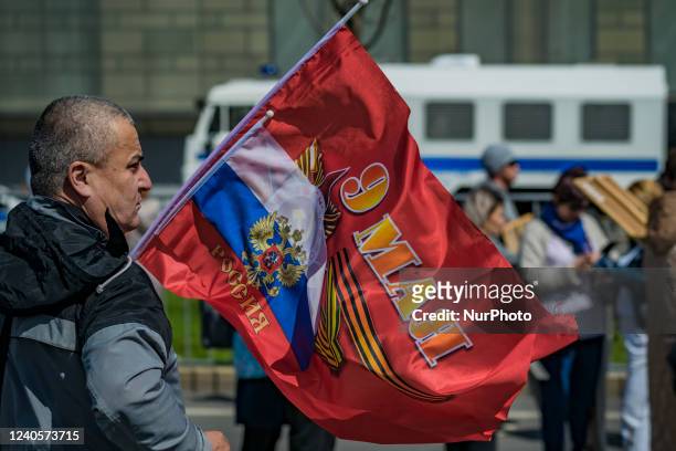 Man holds a russian flag with the date of May 9th in the Inmortal Regiment march in the streets of Moscow during the Victory Day celebrations.