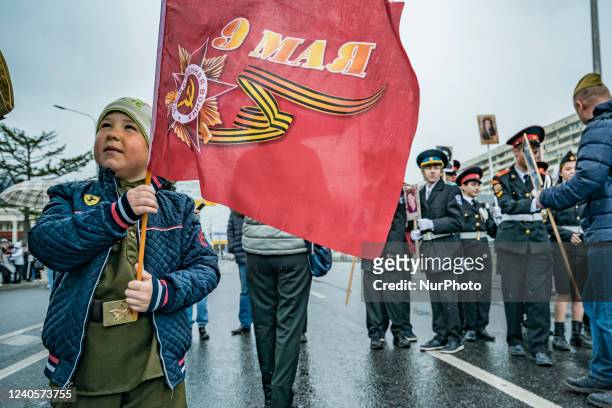 Kid holds a flag about the May 9th celebrations during the Inmortal Regiment march in the streets of Moscow. This march celebrates the soviet victory...