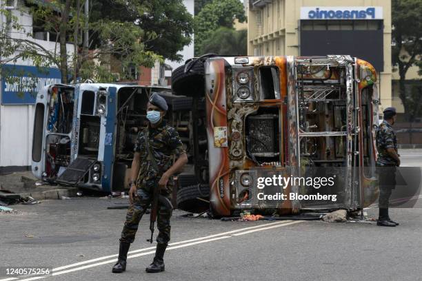 Sri Lankan Air Force officers stand in front of a bus destroyed by protesters in Colombo, Sri Lanka, on Tuesday, May 10, 2022. Violence erupted in...