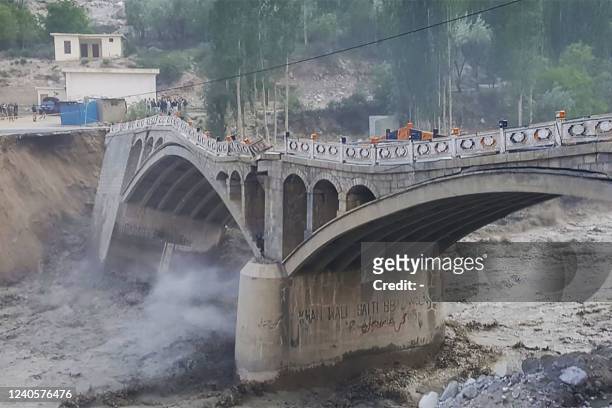 This photograph taken on May 7 shows a bridge partially collapsed due to flash floods cretaed after a glacial lake outburst, in Hassanabad village,...