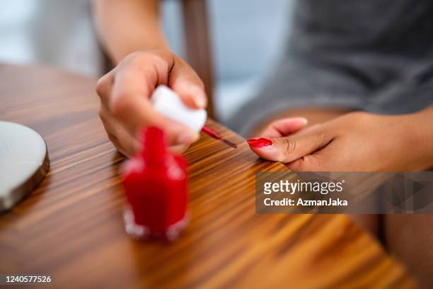 enthusiastic female painting her nails red - painting fingernails stock pictures, royalty-free photos & images