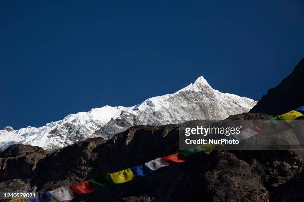 Tibetan - Buddhist religious prayer flag along with the Langtang Lirung peak. Langtang Lirung peak as seen from Langtang village, part of the...