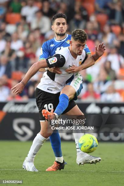 Valencia's Spanish forward Hugo Duro vies with Real Betis' Spanish defender Marc Bartra during the Spanish league football match between Valencia CF...