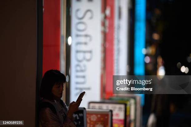 Woman uses her smartphone in front of a SoftBank Corp. Store in Tokyo, Japan, on Tuesday, May 10, 2022. SoftBank Group Corp. Is scheduled to release...