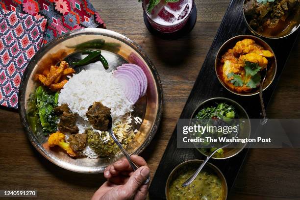 Chef Kesher Jarga puts together of a a plate of the Nepali Set Meal with black daal, mustard greens, cauliflower and goat curry and a Khukuri...