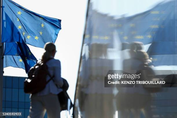 Woman passes by flags of the European Union outside the European commission headquarters in Brussels on May 11, 2022.