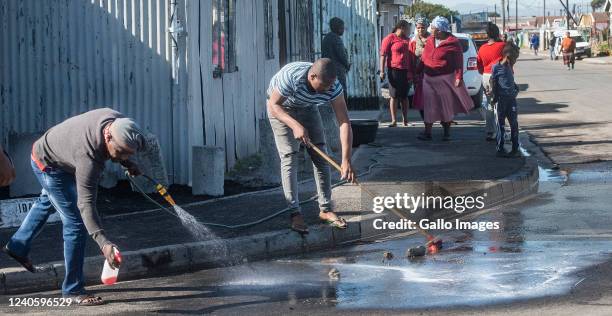 Family members wash away blood at the scene of a shooting in Site C in Khalelitsha where six people were shot and killed and the sixth person died at...