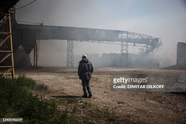 Member of security watches smoke rising from burning storage buildings containing agricultural products after shelling by Russian forces amid the...