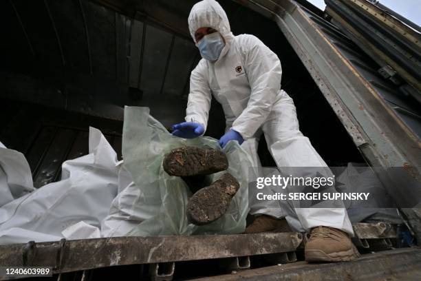 Ukrainian forensics experts examine the body of a Russian soldier exhumed in the village of Zavalivka, west of Kyiv, in a refrigerated rail car...