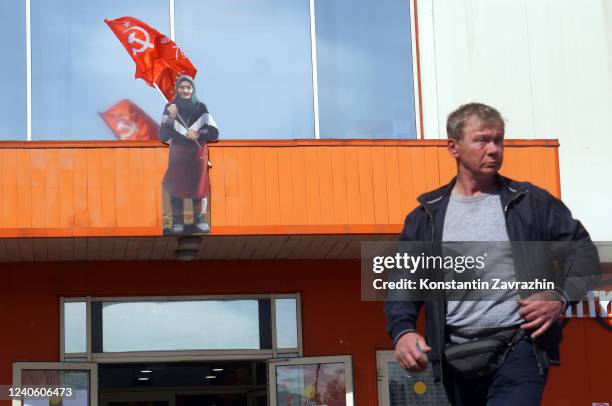 Cardboard figure of an elderly woman holding a Soviet flag is installed on the facade of the shopping center is seen on May 11, 2022 in Moscow,...
