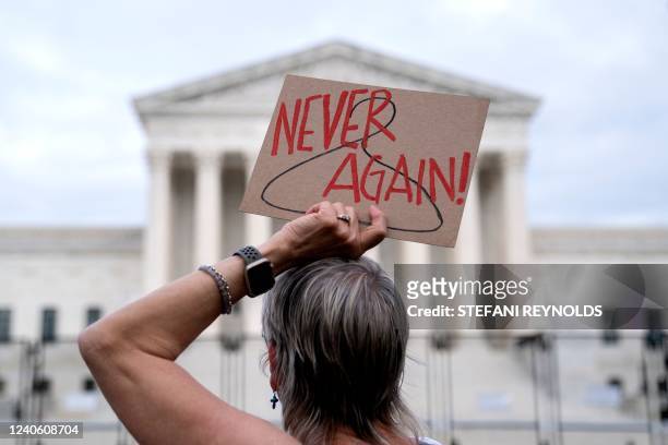 Pro-choice demonstrator holds a sign with a coat hanger, a symbol of the reproductive rights movement, with the words Never Again in front of the US...