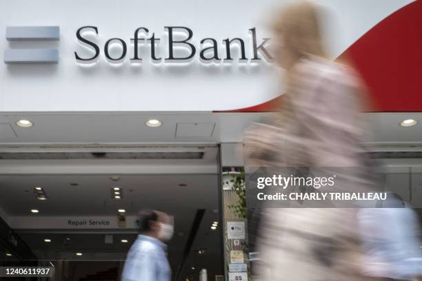 Pedestrians walk past a SoftBank mobile shop in Tokyo on May 12, 2022.