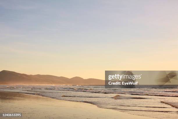 view of the beach in oceanside, oregon during low tide at sunset - côte pacifique photos et images de collection