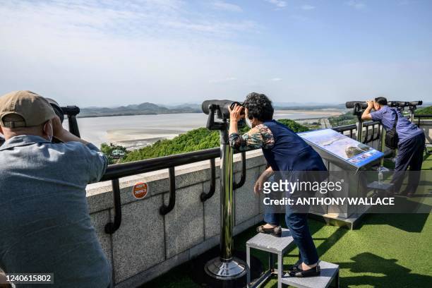 Visitors use binoculars to look towards the North Korean side of the Demilitarised Zone from the Odusan Unification Tower in Paju on May 12, 2022.