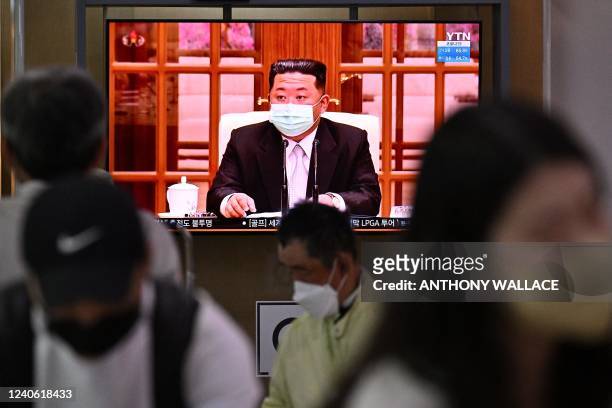 People sit near a screen showing a news broadcast at a train station in Seoul on May 12 of North Korea's leader Kim Jong Un appearing in a face mask...