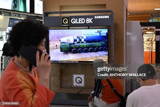 Woman walks past a television screen showing file footage of a North Korean missile test during a news broadcast in Seoul on May 12 after Seoul's...