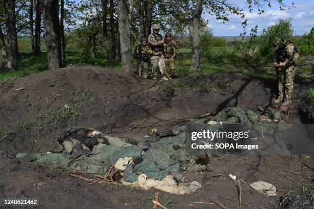 Forensic military investigators check the mass grave with eleven Russian corpses in the village of Vil'khivka. According to the coroners, the bodies...