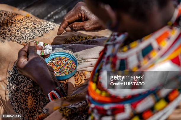 Samburu woman works making traditional Samburu ornaments and jewelry out of beads next to a house in Kalama Conservancy, Samburu County, Kenya on May...
