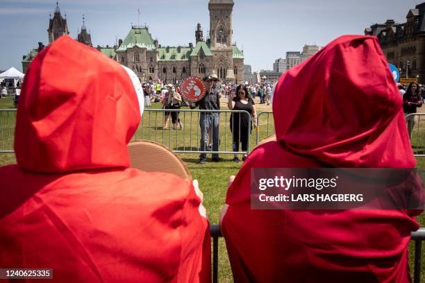 People dressed in red robes as characters from The Handmaid's Tale face pro-life protesters on Parliament Hill during the National March for Life in...