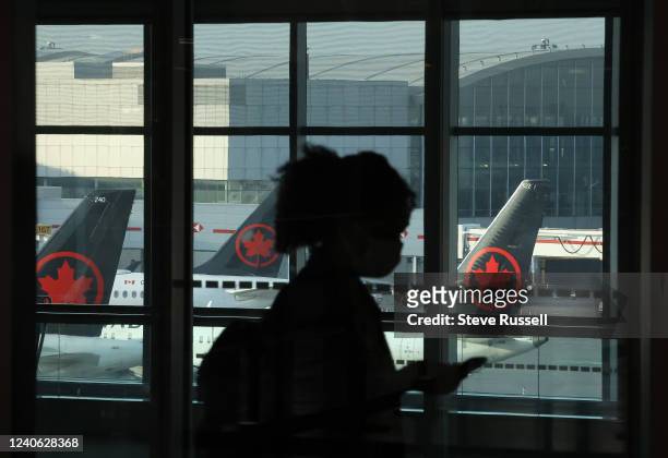 Passengers move along towards their flights with Air Canada airplanes in the background at Pearson International Airport in Mississauga. May 12, 2022.