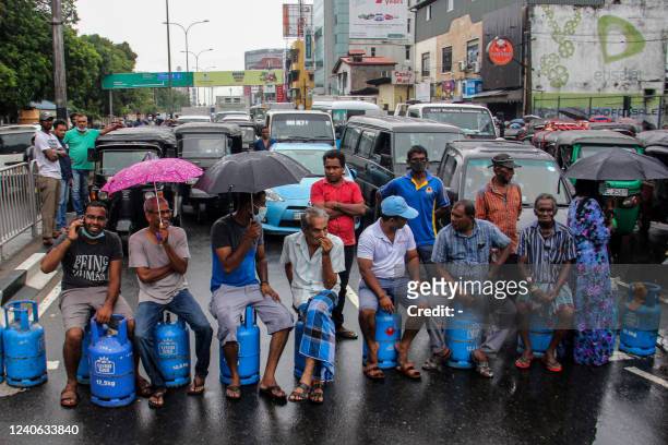 People sit on empty Liquified Gas Cylinders as they block a road to protest against shortage of fuel and cooking gas in Colombo on May 13, 2022. Sri...