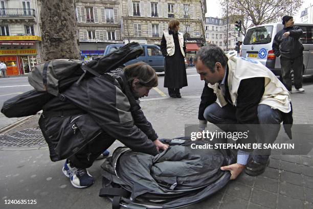 Un bénévole de "Médecins du monde" aide un SDF à plier sa tente sous les yeux de la responsable de la mission SDF de l'organisation, Graziella Robert...