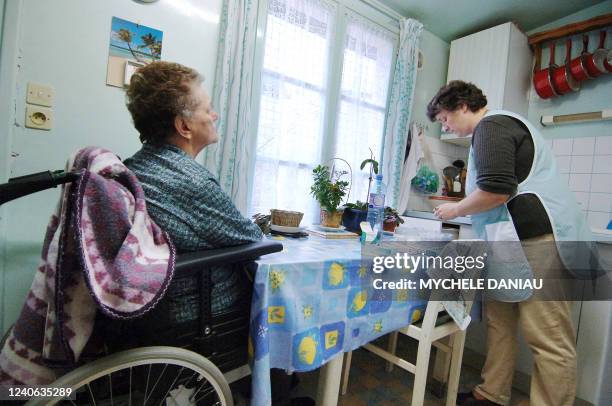 Employée de l'aide à domicile en milieu rural Marilyne prépare les médicaments sous le regard d'Yvette dans sa cuisine, 05 décembre 2006 à Mézidon....