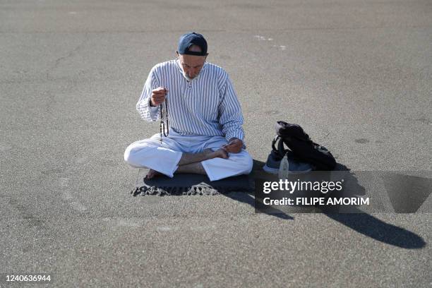 Pilgrim prays on the ground, at the Shrine of Fatima, central Portugal, on May 13, 2022. - Thousands of pilgrims converged on the Fatima Sanctuary to...