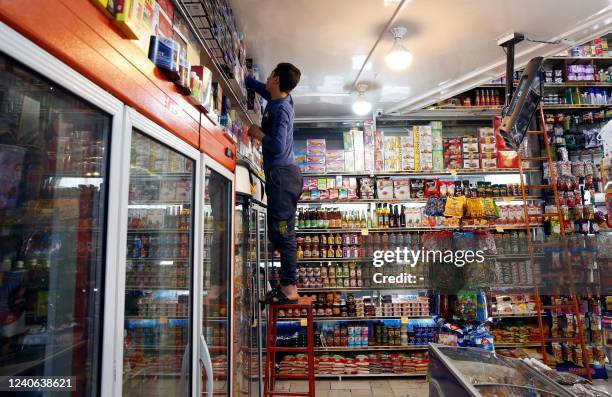 An Iranian employee arranges merchandise at a food store in the capital Tehran on May 13 as prices on basic goods soar. - Hundreds of people have...