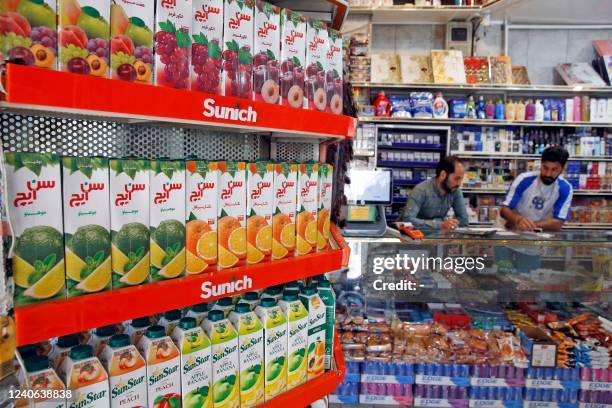 Iranians work at a food store in the capital Tehran on May 13 as prices on basic goods soar. - Hundreds of people have taken to the streets in cities...