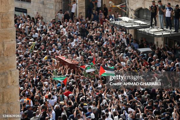 Palestinian mourners wave national flags as they carry the casket of slain Al-Jazeera journalist Shireen Abu Akleh, during her funeral procession...