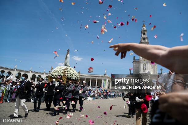 Pilgrims throw flower petals to a statue of Our Lady of Fatima during a procession at the Shrine of Fatima, central Portugal, on May 13, 2022. -...