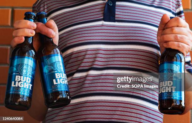 In this photo illustration, a man holds Bud Light beer bottles.