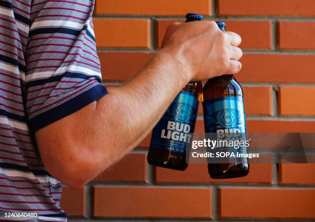 In this photo illustration, a man holds Bud Light beer bottles.