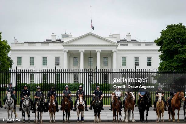 Law enforcement officers take a group photo as the American flag flies at half-staff at the White House as the United States passes one million...